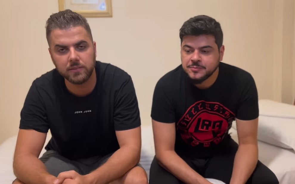 Zé Neto e Cristiano sentados em uma cama, de roupas pretas, em vídeo para comunicar o cancelamento do show no VillaMIx Festival