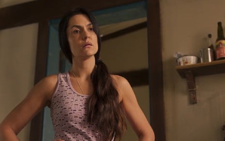 Paula Barbosa grava cena como Zefa em Pantanal; ela está com o cabelo predo de lado e usa camiseta regata