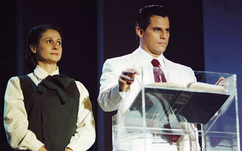 Zezé Polessa e Edson Celulari estão em uma espécie de palanque em cena de Decadência (1995)