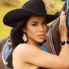 Foto de Larissa Tomásia; ela usa chapéu de fazendeiro e está ao lado de cavalo