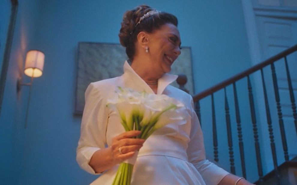 Eliane Giardini sorri e está vestida de noiva em cena da novela Terra e Paixão