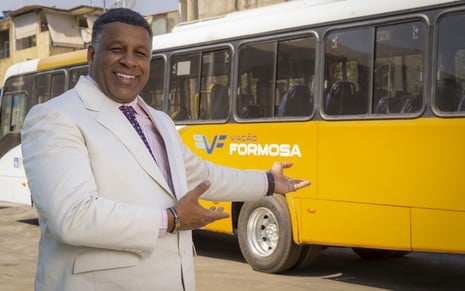 Aílton Braça posa mostrando um ônibus amarelo com o nome de sua empresa, Viação Formosa