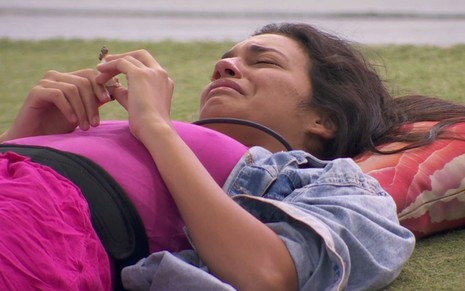 Foto mostra Alane Dias chorando deitada no gramado do BBB 24