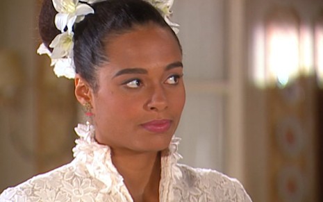 A atriz Aisha Jambo vestida de noiva, com expressão séria em cena de Alma Gêmea