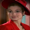 A atriz Flávia Alessandra com expressão séria, chapéu e terno vermelhos em cena de Alma Gêmea