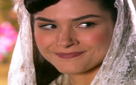 A atriz Fernanda Machado de véu branco na cabeça, com leve sorriso de boca fechada, em cena da novela Alma Gêmea