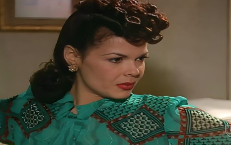 Andrea Avancini em cena como Terezinha em Alma Gêmea, olhando para a direita, séria, com vestido verde