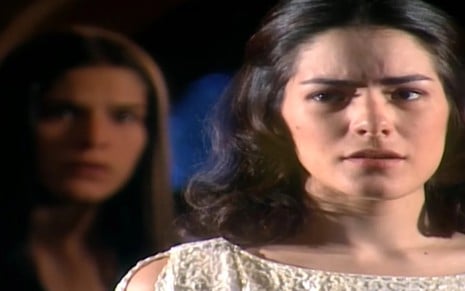 A atriz Priscila Fantin no plano de fundo, com expressão assustada, e a atriz Liliana de Castro em destaque, com expressão séria em cena de Alma Gêmea