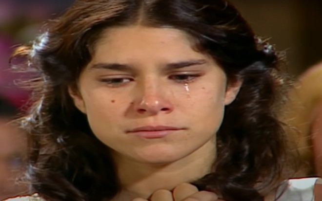 A atriz Priscila Fantin debruçada sobre um túmulo de cemitério, em cena como Serena em Alma Gêmea