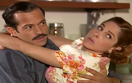 Os atores Malvino Salvador e Drica Moraes abraçados, com expressões de desconfiança, em cena de Alma Gêmea