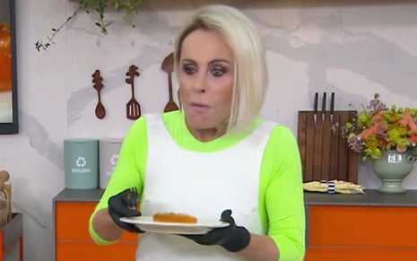 Ana Maria Braga de boca cheia, comendo um doce de maracujá, durante o Mais Você