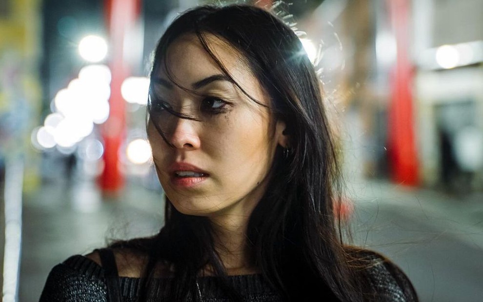 Em cena de As Five, Ana Hikari está com a maquiagem borrada, olhando para o nada, no meio da rua