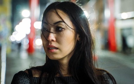 Em cena de As Five, Ana Hikari está com a maquiagem borrada, olhando para o nada, no meio da rua