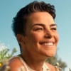 Ana Paula Arósio sorri em um campo florido em comercial para marca de suplementos de uma rede de farmácias
