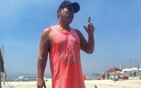 De boné e camisa rosa, Andre Marques conversa com alguém na praia