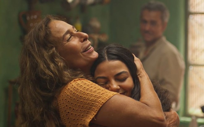 Zefa (Andrea Beltrão) abraça Quinota (Larissa Bocchino) em cena de No Rancho Fundo, ao fundo está Tico (Alexandre Nero)