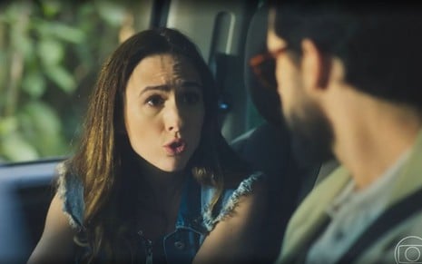 A atriz Tatá Werneck com expressão de choque dentro de carro com o ator Rainer Cadete em cena de Terra e Paixão