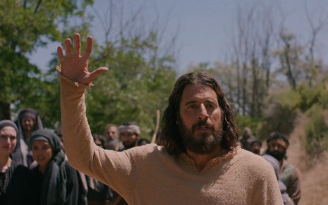 Caracterizado como Jesus, Jonathan Roumie ergue o braço em cena da série The Chosen