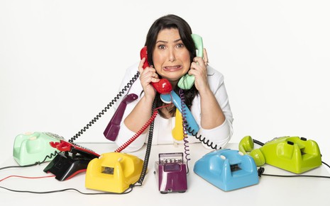 Mariana Xavier faz careta enquanto segura vários telefones em foto promocional da peça Antes do Ano que Vem