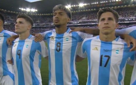 Três jogadores Argentinos abraçados durante a execução do hino nacional na Olimpíada de Prais