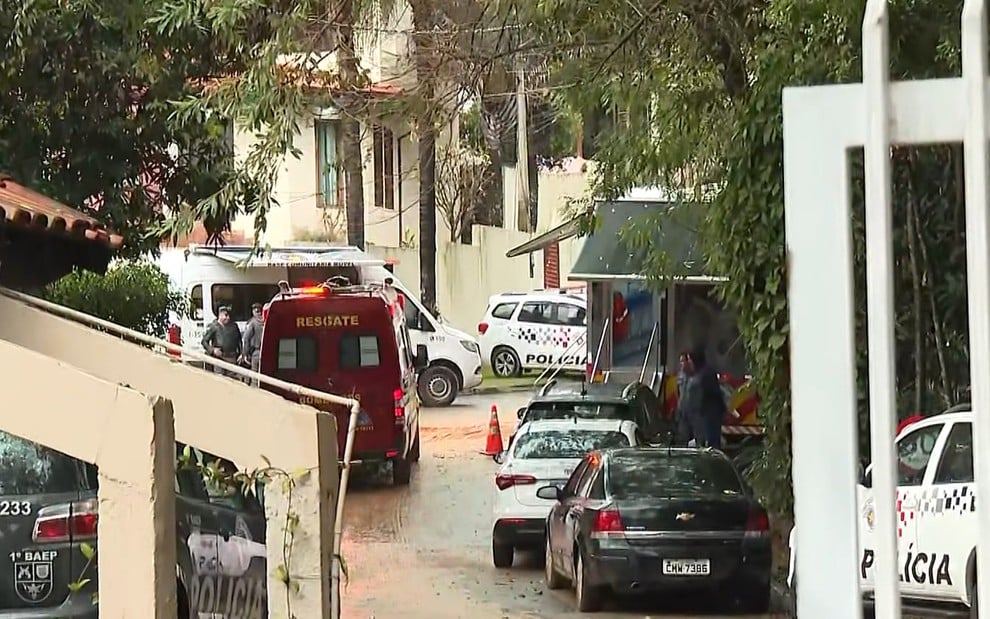 Imagem mostra carros da polícia militar de São Paulo e ambulância por trás de cancela do condomínio