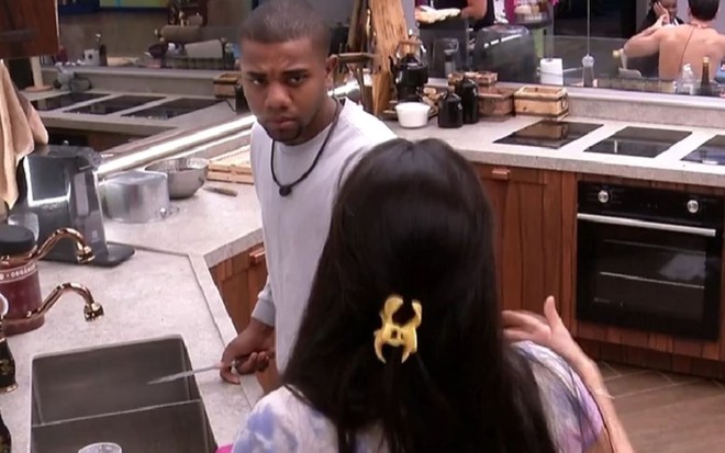 Davi Brito usa uma camisa branca e encara Giovanna Lima --de costas para a câmera; os dois estão na cozinha da Xepa do BBB 24