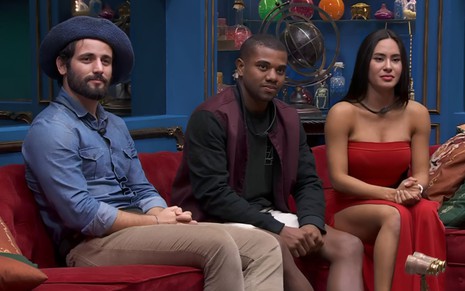 Matteus Amaral, Davi Brito e Izabelle Nogueira estão sentados no sofá, na sala do BBB 24