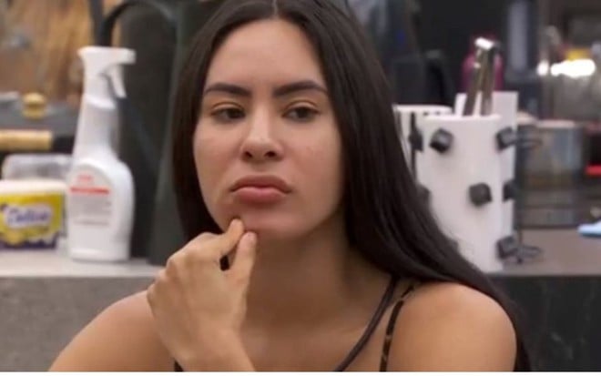 Isabelle Nogueira está com os dedos no queixo, em expressão pensativa, na cozinha do BBB 24