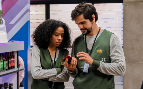 Pórcia (Beatriz Oliveira) olha celular na mão de Vitor (Ciro Sales)