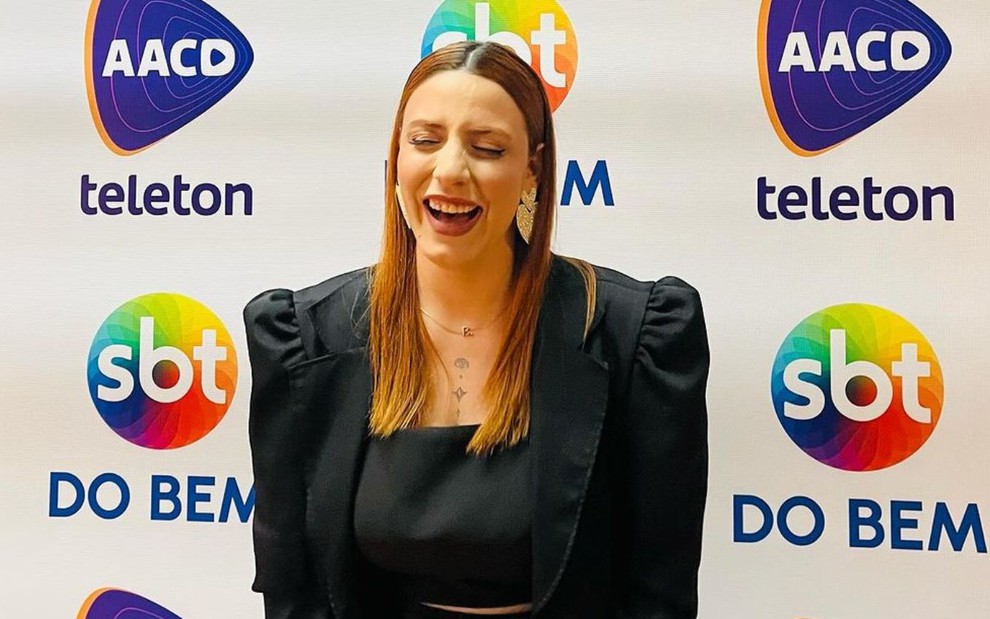 Bianca Sessa dá risada em frente ao painel do Teleton 2023