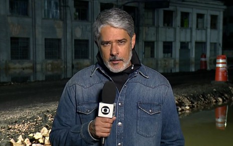 William Bonner em uma rua alagada com o microfone da Globo durante o Jornal Nacional