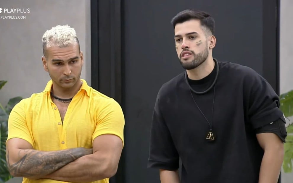 Brenno Pavarini e Kaio Perroni estão em pé e lado a lado na sala da Mansão de A Grande Conquista 2