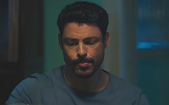 Em cena de Terra e Paixão, Cauã Reymond está com a expressão séria, olhando para baixo
