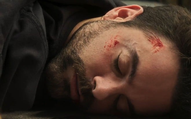 Em cena de Fuzuê, Pedro Carvalho está caído no chão com o rosto ferido