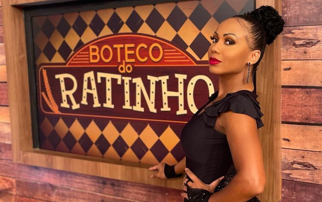 Foto mostra Cintia Mello em frente a painel do programa do Ratinho