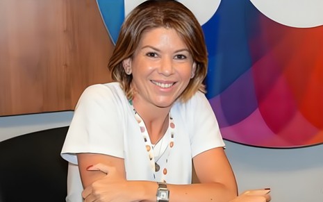 Daniela Beyruti, CEO do SBT, em escritório da emissora, sorrindo, de bulsa branca