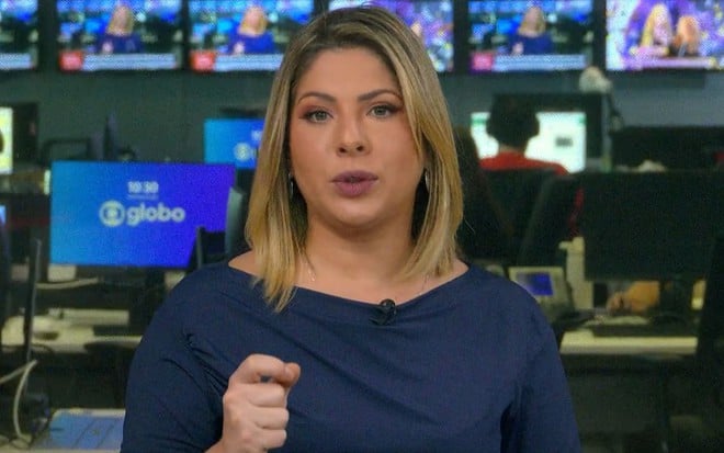 Daniela Lima usa uma blusa azul e está no cenário do Conexão GloboNews