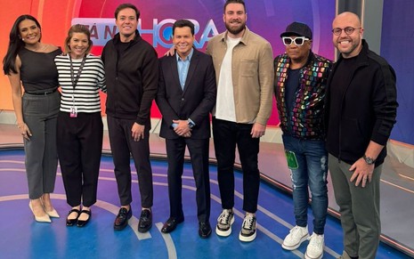 Márcia Dantas, Daniela Beyruti, André Valadão e Marcão do Povo posam no cenário do Tá na Hora; também estão na foto Liminha e mais duas pessoas