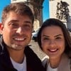 Danilo Santos Romano e a namorada, Thalita Valente, sorriem em frente ao Arco do Triunfo, em Paris, França