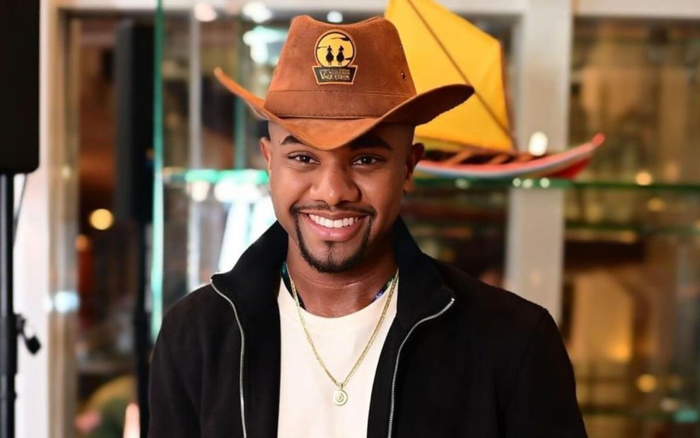 Davi Brito sorri e está com um chapéu de cowboy na cabeça