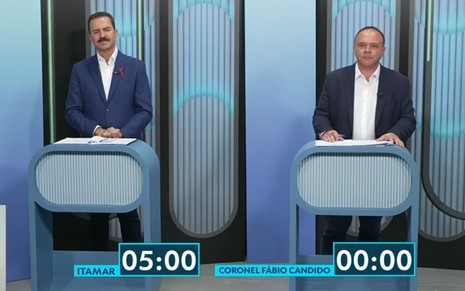 Itamar Borges e coronel Fábio Candido estão em pé atrás de pulpito no debate da TV TEM