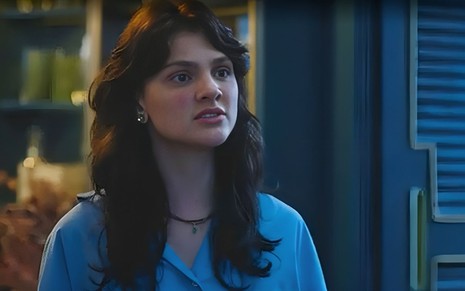 Em cena de Terra e Paixão, Debora Ozório está vestida de azul e falando com alguém em tom de discussão
