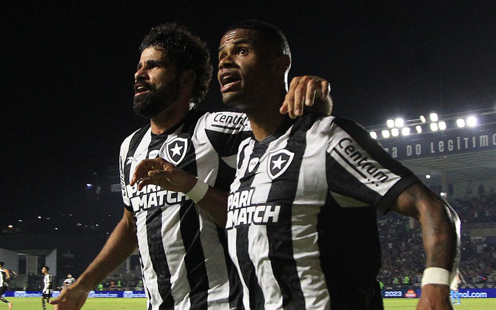 Diego Costa e Júnior Santos correm abraçados para comemorar gol do Botafogo; eles usam uniforme preto e branco do clube