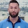 Diego Hypolito usa uma camiseta azul claro com o símbolo da Globo; ela está sério