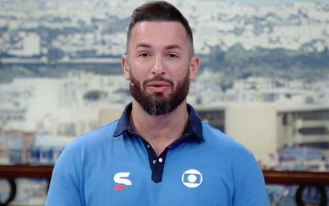 Diego Hypolito usa uma camiseta azul claro com o símbolo da Globo; ela está sério