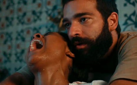 Maria Santa (Duda Santos) grita de dor e é amparada por José Inocêncio (Humberto Carrão), que a abraça por trás em cena de Renascer