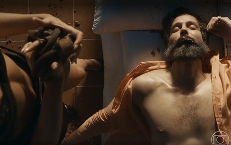 Em cena de Renascer, Vladimir Brichta está deitado sem camisa, depois do sexo; enquanto Sophie Charlotte está de lingerie, em pé, ao seu lado