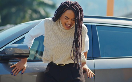 A atriz Lucy Ramos com expressão de dor e sofrimento, em frente a carro em cena de Família É Tudo
