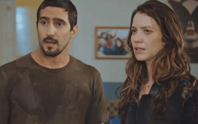 Os atores Renato Góes e Nathalia Dill um ao lado do outro, sérios, em cena de Família È Tudo