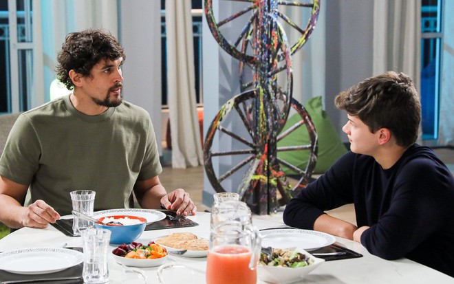 Mauro (Felipe Roque) e Alex (Gianlucca Mauad) sentados na mesa de jantar